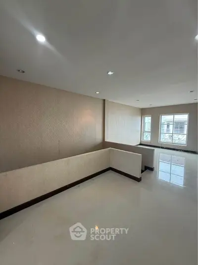 Spacious living room with elegant wallpaper and large windows offering natural light.