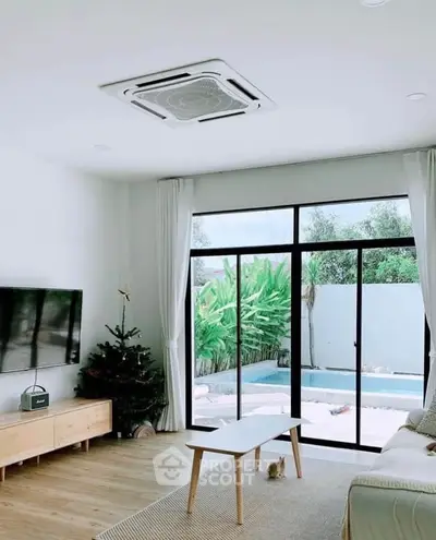 Modern living room with pool view, sleek furniture, and natural light.