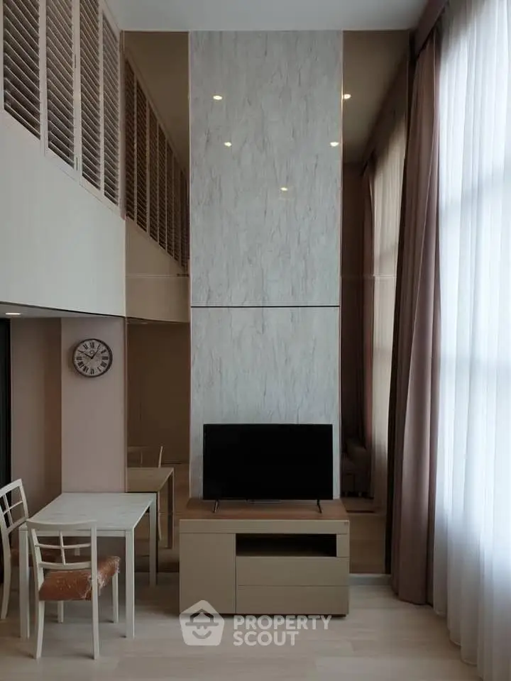 Modern living room with high ceiling and stylish decor in a contemporary apartment.