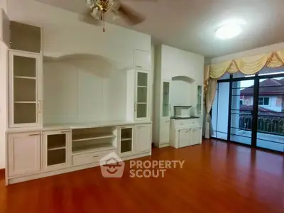 Spacious living room with built-in cabinets and large windows overlooking a balcony.