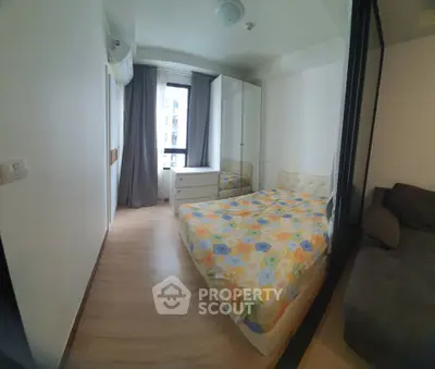 Cozy bedroom with floral bedding, mirrored wardrobe, and natural light from window.