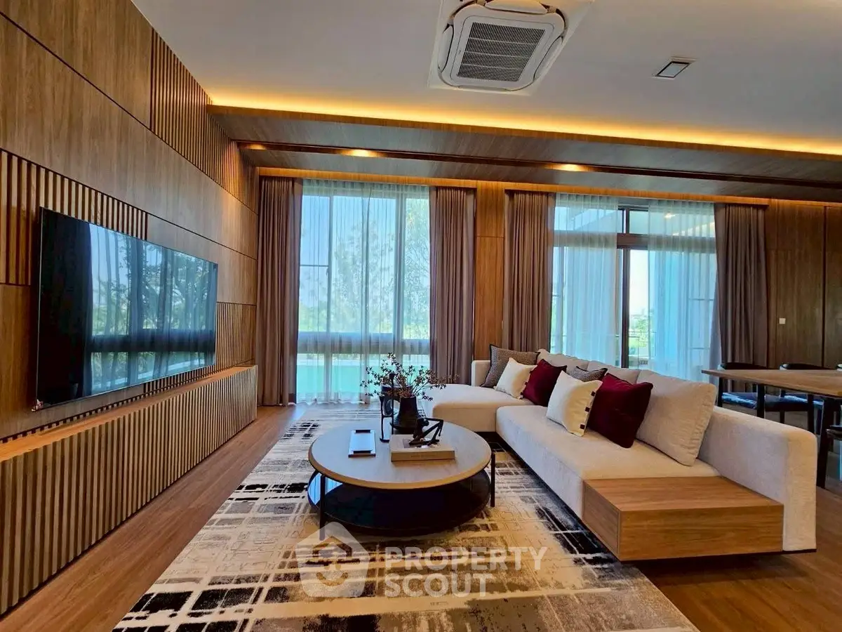 Luxurious modern living room with elegant wooden paneling and large windows offering scenic views.