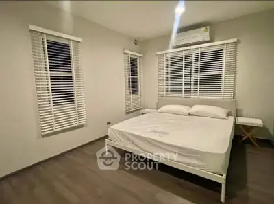 Spacious bedroom with modern decor and large windows for natural light.