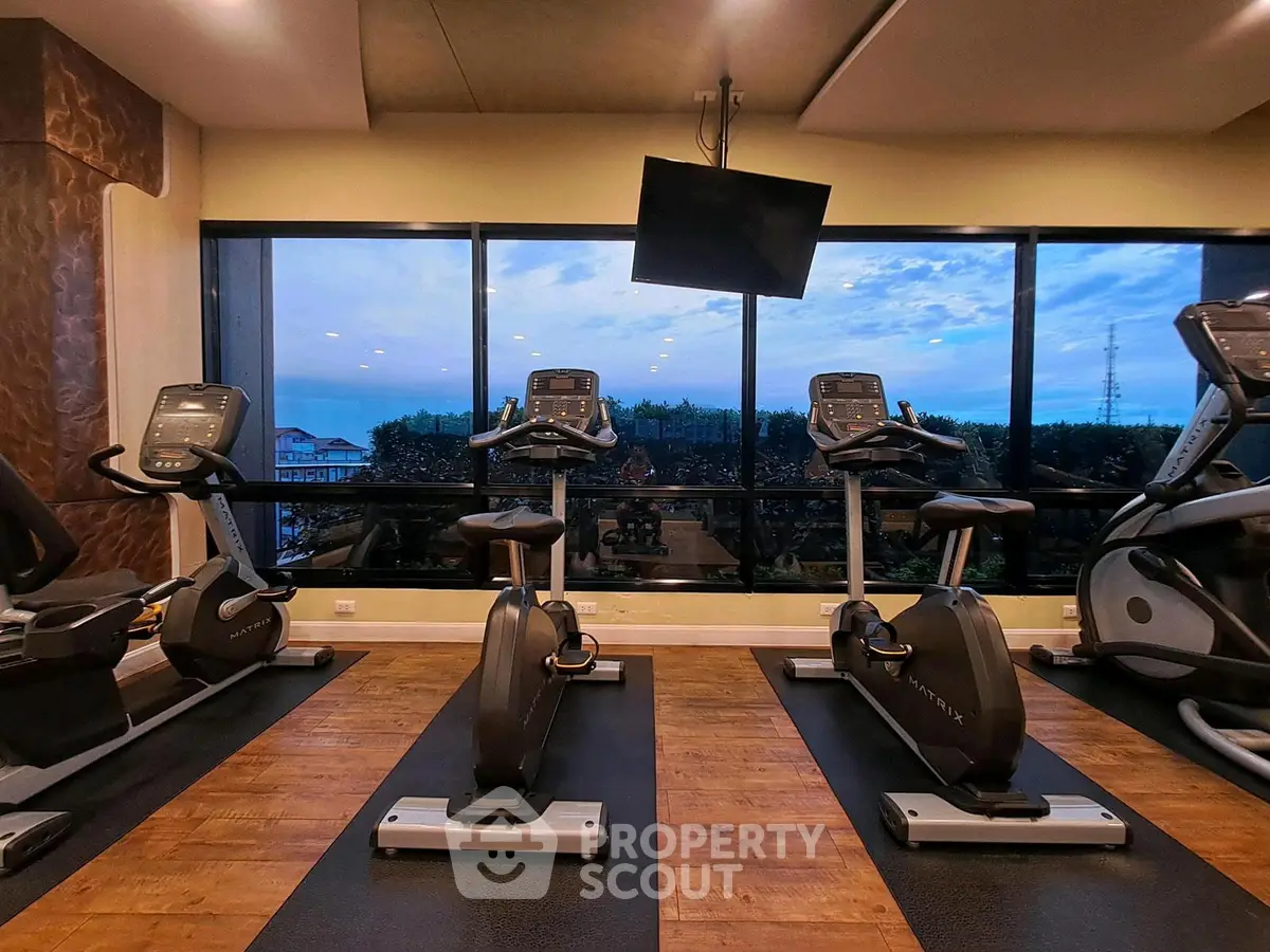 Modern gym with exercise bikes and scenic window view in luxury building.