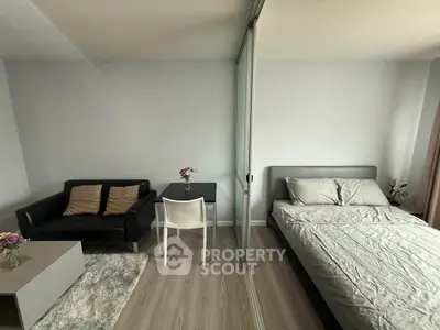 Modern studio apartment with cozy living area and bedroom separated by glass partition.