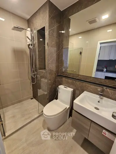 Modern bathroom with sleek design, featuring a glass shower and contemporary fixtures.