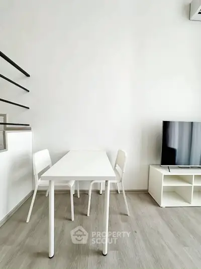 Modern minimalist living room with sleek white furniture and flat-screen TV, perfect for contemporary urban living.