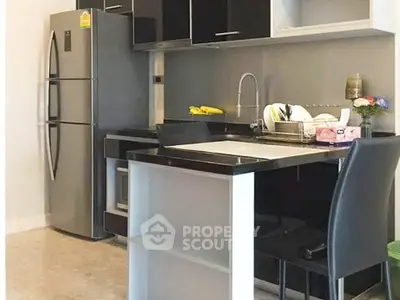 Modern kitchen with sleek black cabinets and stainless steel appliances in a stylish apartment.