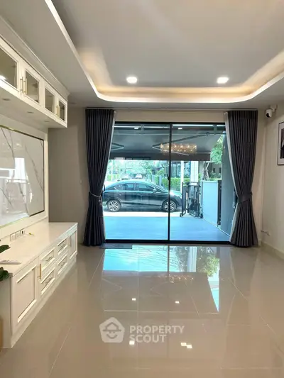 Spacious living room with elegant ceiling lights and large sliding glass doors leading to a patio.