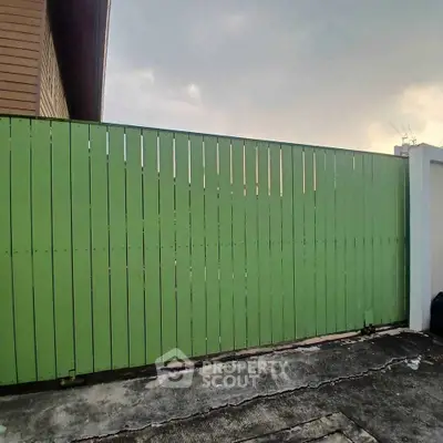 Modern green wooden fence enclosing residential property with concrete base.