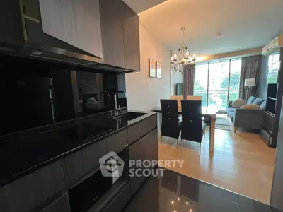 Modern open-plan kitchen and living room with elegant chandelier and large windows.