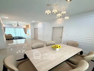 Elegant dining area with modern lighting and spacious living room in luxury apartment.