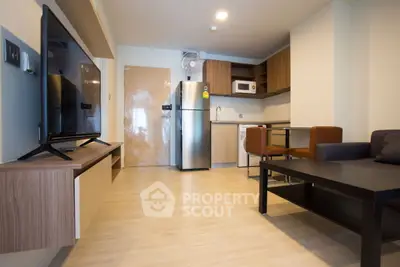 Modern living room with open kitchen, featuring sleek appliances and stylish furniture.