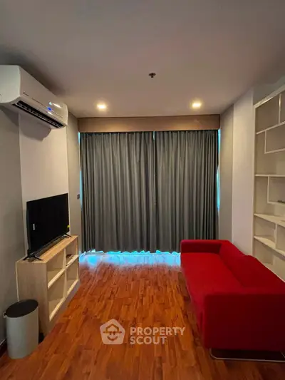 Modern living room with red sofa, TV, and air conditioning in a cozy apartment.