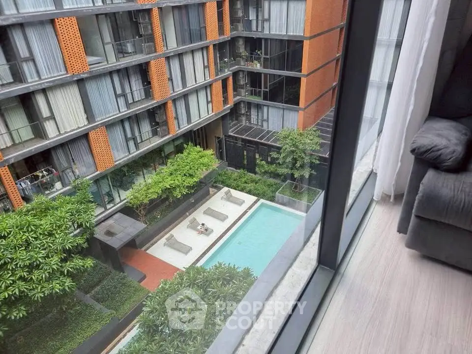 Modern apartment view with pool and lush greenery from high-rise window