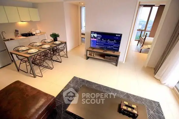 Modern open-layout living room with dining area and kitchen, featuring stylish furniture and a cozy ambiance.