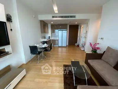 Modern living room with open kitchen, stylish furniture, and wooden flooring in a contemporary apartment.