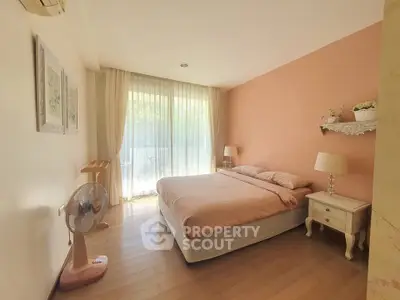 Cozy bedroom with soft pink accents and large window for natural light