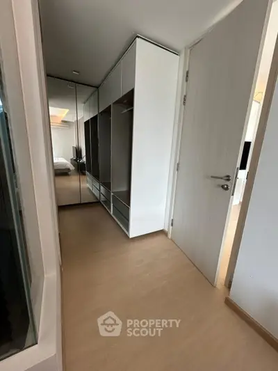 Modern bedroom with mirrored wardrobe and wooden flooring