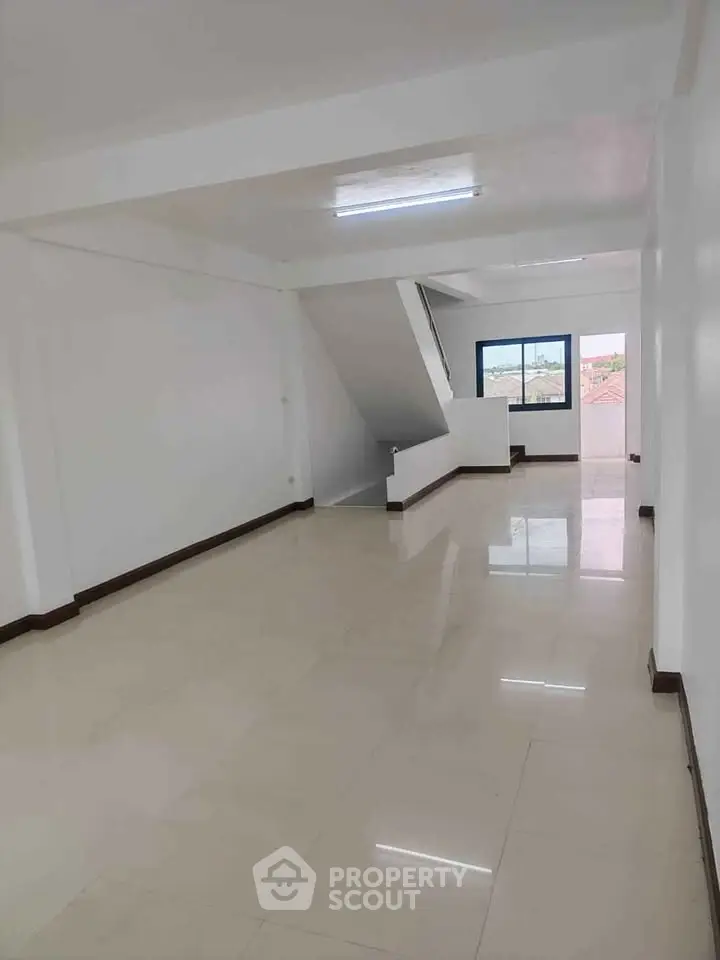 Spacious open-plan living area with large windows and glossy tiled floors, perfect for modern living.