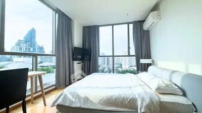 Spacious bedroom with city view and modern furnishings in high-rise apartment.