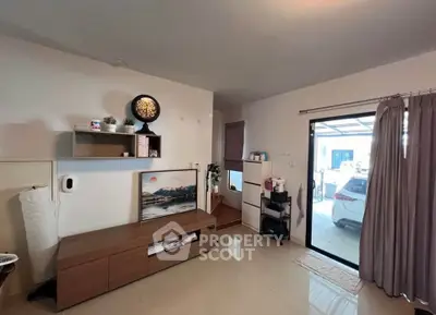 Modern living room with sleek furniture and large window overlooking driveway.