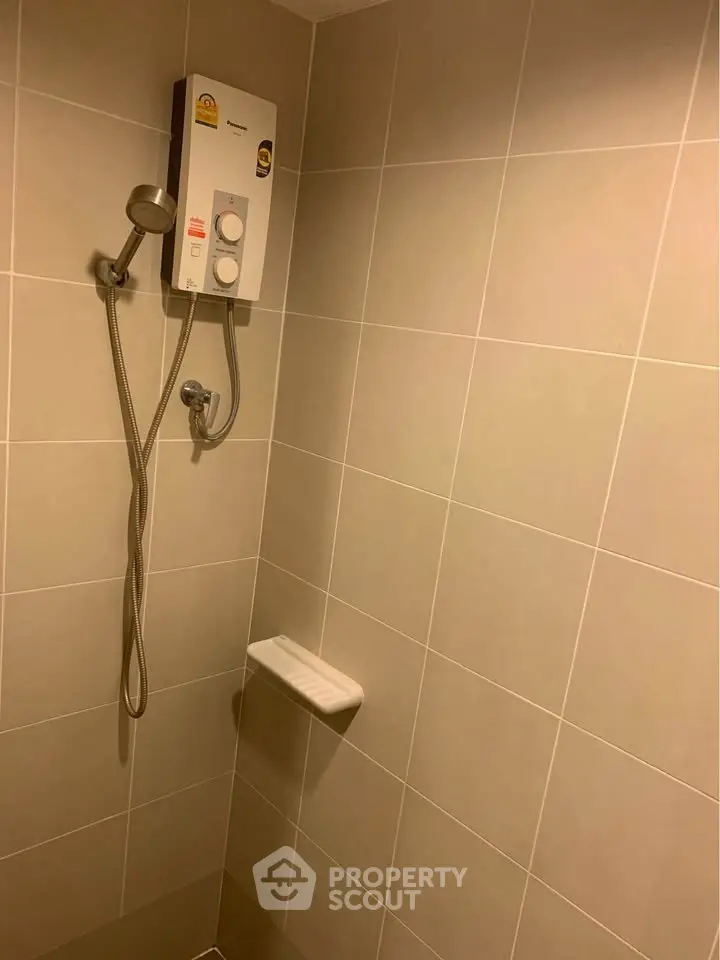 Modern bathroom with tiled walls and electric shower unit, ideal for comfortable living.