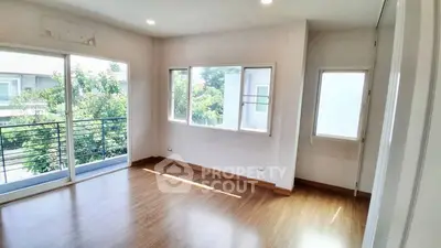 Bright and airy room with large windows and wooden flooring, perfect for a cozy living space.