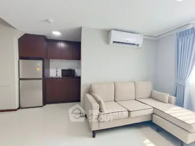Modern living room with beige sectional sofa and compact kitchen area.