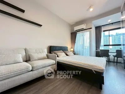 Modern bedroom with city view, featuring cozy sofa and stylish decor.