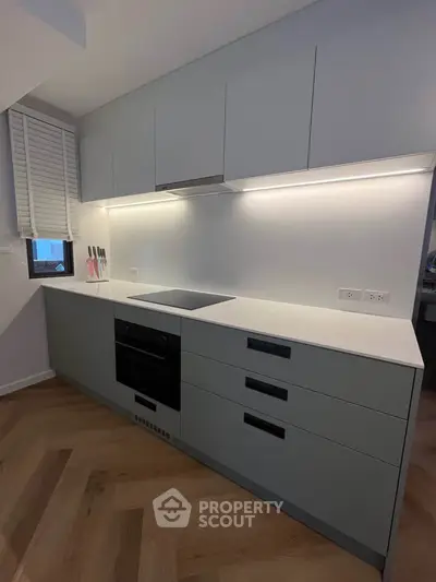 Modern kitchen with sleek cabinetry and built-in oven, featuring under-cabinet lighting.