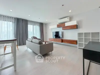 Spacious modern living room with sleek furniture and large windows offering natural light.