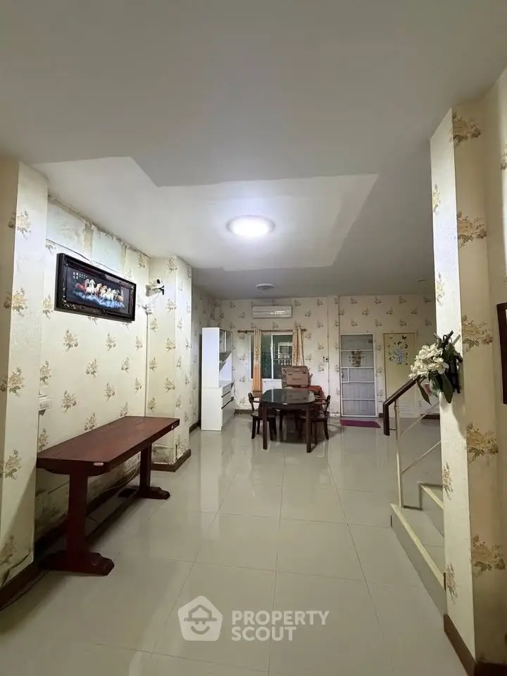 Spacious living room with elegant decor and dining area, featuring floral wallpaper and modern lighting.