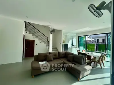 Spacious modern living room with open layout and pool view, featuring stylish furniture and abundant natural light.