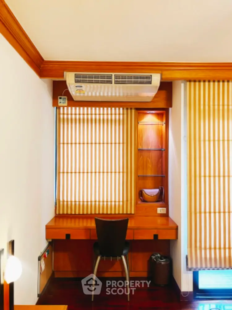 Cozy study area with wooden desk and chair, featuring air conditioning and striped blinds.