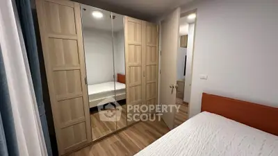 Modern bedroom with mirrored wardrobe and wooden flooring in cozy apartment.