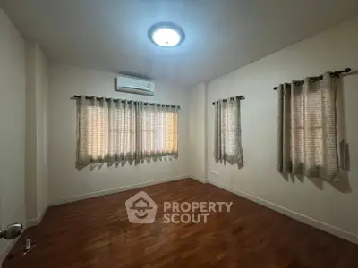 Spacious empty bedroom with wooden flooring and natural light