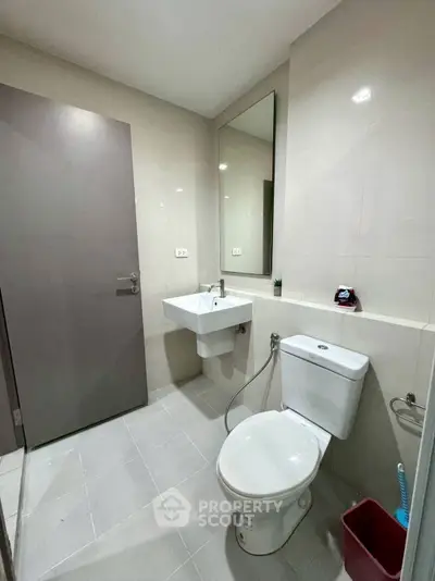 Modern bathroom with sleek fixtures and neutral tones, featuring a wall-mounted sink and toilet.