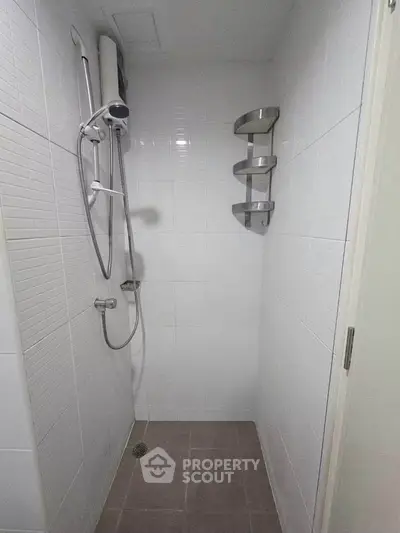 Compact bathroom shower area with modern fixtures and corner shelf
