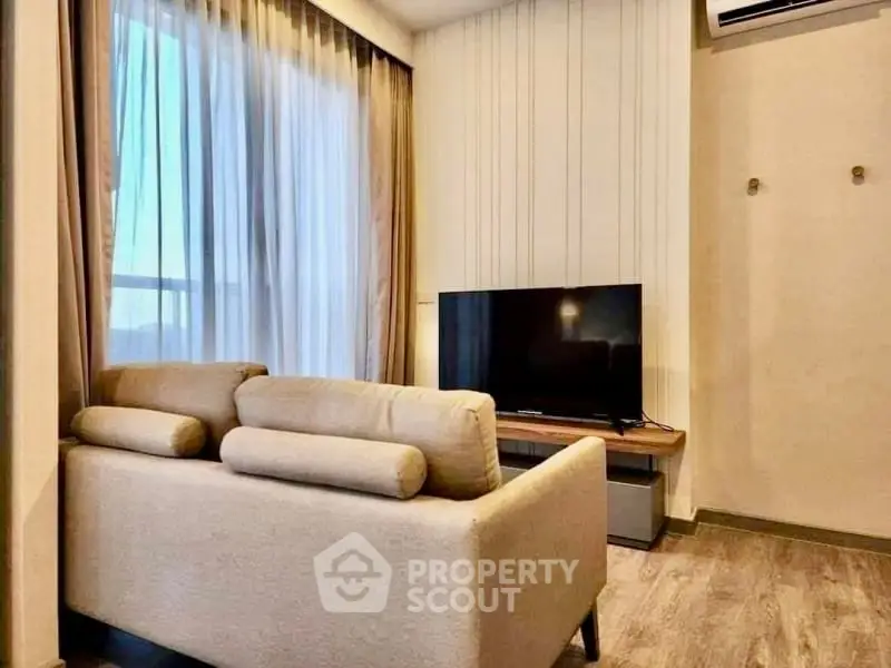 Cozy living room with modern sofa and flat-screen TV, perfect for relaxation.
