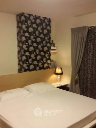 Cozy bedroom with elegant floral wallpaper and soft lighting, perfect for relaxation.