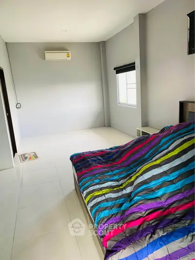 Spacious bedroom with colorful bedding and air conditioning in modern home.