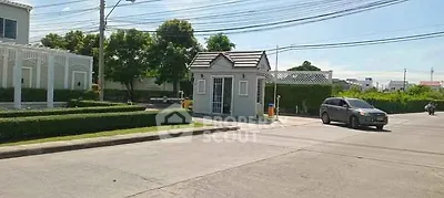 Charming residential entrance with lush greenery and secure gated access.