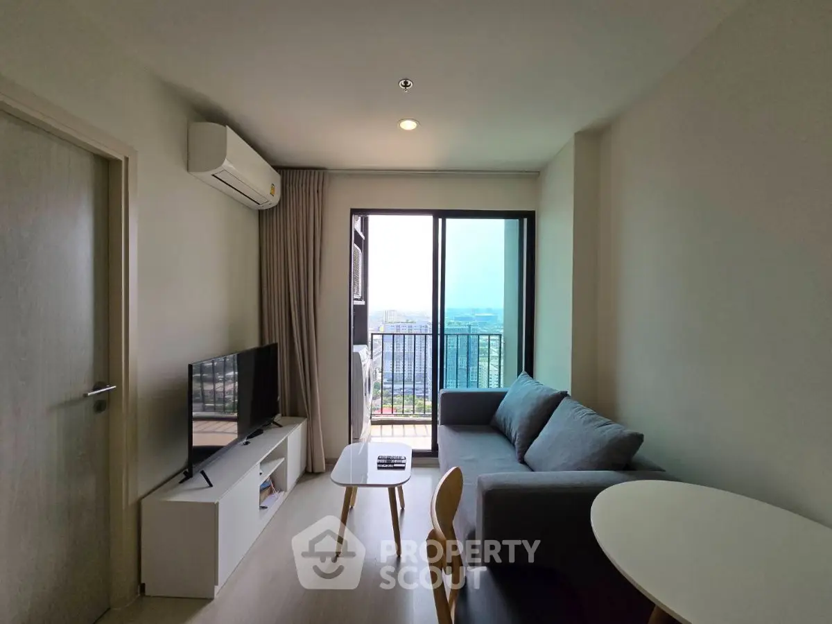 Modern living room with balcony view, featuring sleek furniture and natural light.