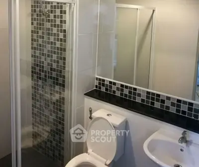 Modern bathroom with sleek shower and stylish black tile accents.
