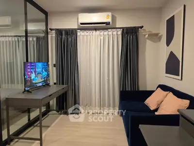 Modern living room with sleek furniture and large window, featuring a cozy blue sofa and wall-mounted air conditioner.