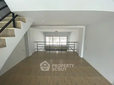 Spacious modern interior with wooden flooring and large window, ideal for versatile living space.