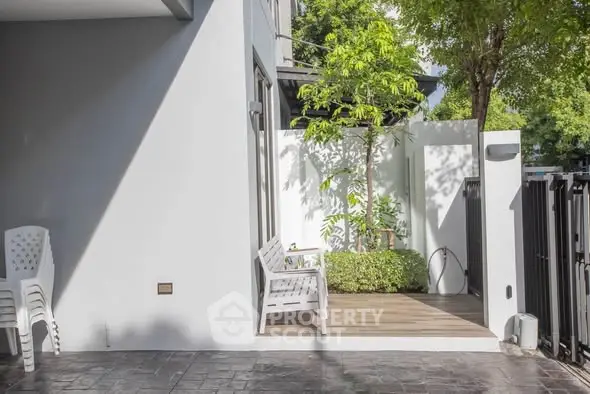 Charming outdoor patio with lush greenery and modern seating area, perfect for relaxation and entertaining.