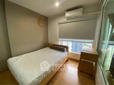 Cozy bedroom with modern furnishings and city view, featuring a comfortable bed and air conditioning.