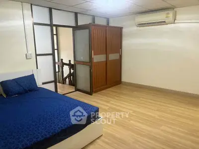 Spacious bedroom with wooden flooring and modern air conditioning unit.